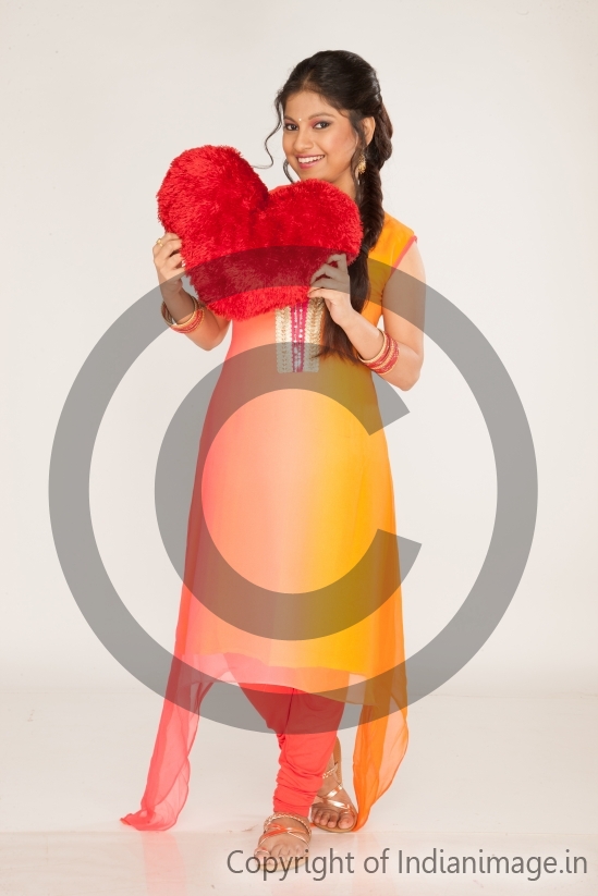 Indian girl holding a red heart pillow